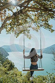 woman portrait enjoying nature from a hill top sitting on a swin