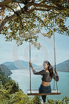 woman portrait enjoying nature from a hill top sitting on a swin