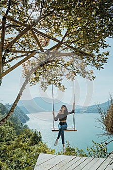 woman portrait enjoying nature from a hill top sitting on a swin