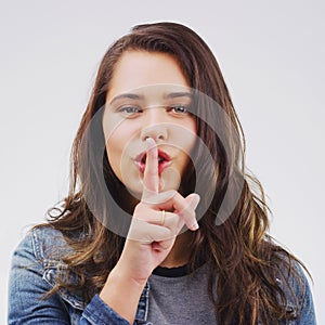 Woman, portrait and finger with rumor, studio and silence for mystery announcement. Model, gossip and hush with secret