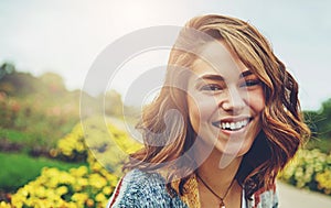 Woman, portrait and flowers with smile for travel in autumn environment, countryside or outdoor. Female person, face and