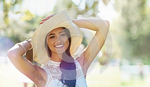 Woman, portrait and hat for relaxing in park or garden, smiling and joyful on summer holiday. Female person, peace and