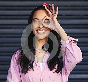 Woman, portrait and ok gesture over eye, fun and playful with POV or lens for humor on dark background. Hand, vision or