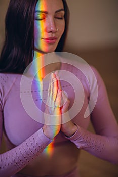 Woman portrait practicing meditation and yoga with rainbow light on her body and face