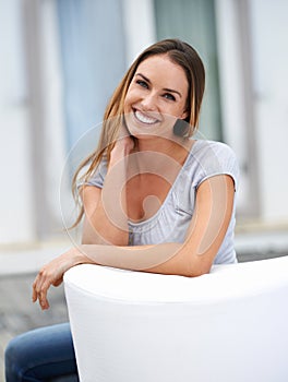 Woman, portrait and relax on sofa on patio, calm and comfort with positive mood for leisure outdoor. Rest, lounge in