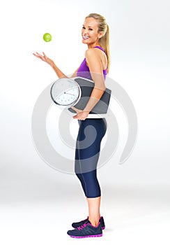 Woman, portrait and scale or apple for balance, studio and excited for results of diet or detox. Female person