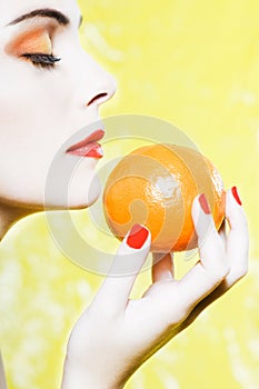 Woman portrait smelling an orange tangerine fruit