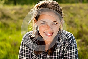 Woman, portrait and smile in grass field for spring with happiness, flowers and wellness. Female gen z person, rest and