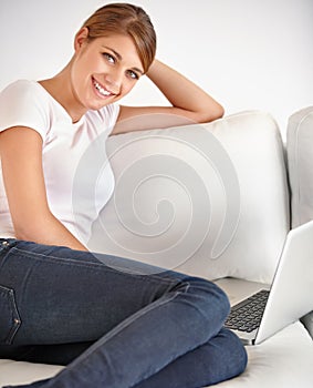 Woman, portrait and smile with laptop on sofa to watch movies, digital subscription and streaming multimedia at home