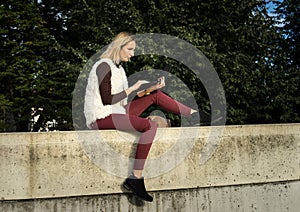Woman portrait in summer. Girl is sitting outside an office and holding a tablet. Female with notebook