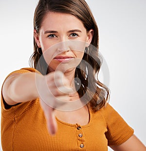 Woman, portrait and thumbs down rejection in studio for vote, voice or opinion, rating or fail on white background. Face