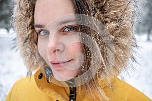 Woman portrait under snow with snowflakes on hear, lookin straight at camera. lifestyle