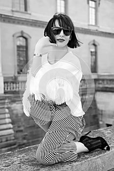 Woman pose on stone fence on house facade