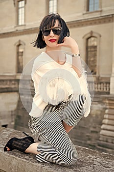 Woman pose on stone fence on house facade