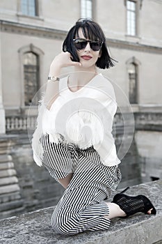 Woman pose on stone fence on house facade