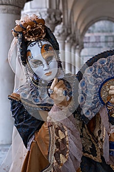 Woman poses in ornate, detailed costume, mask and hat, at the Doges Palace, St Mark`s Square during during Venice Carnival, Italy