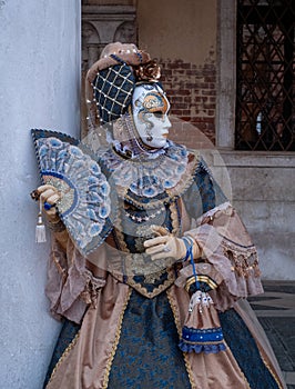 Woman poses in ornate, detailed costume, mask and hat, at the Doges Palace, St Mark`s Square during during Venice Carnival, Italy