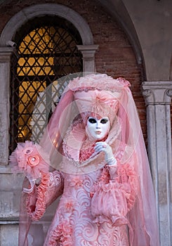 Woman poses in ornate, detailed costume, mask and hat, at the Doges Palace, St Mark`s Square during during Venice Carnival, Italy