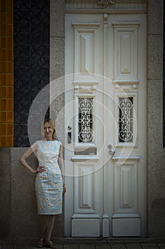 A woman poses outside the tall white doors of a traditional Portuguese house in Porto.