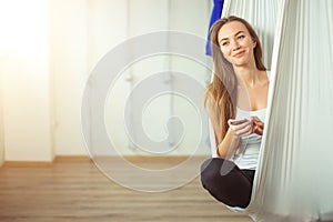 Woman posing in anti-gravity aerial yoga hammock. relax with phone