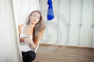 Woman posing in anti-gravity aerial yoga hammock. relax with phone