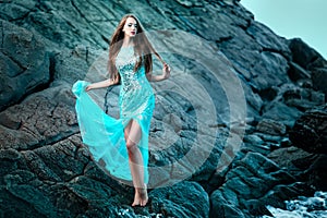 Woman posing on a beach with rocks