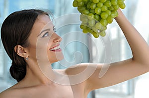 Woman posing with a bunch of grapes and smiling.