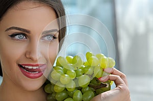 Woman posing with a bunch of grapes and smiling.