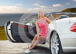 Woman posing in convertible car over big sur coast