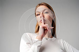 Woman Posing With Finger on Lips Hush Sign in Studio