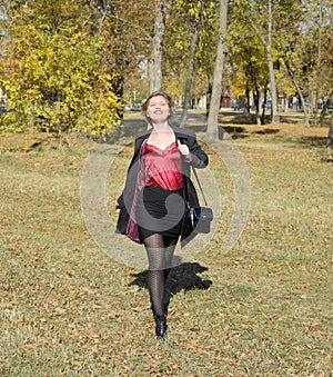 A woman is posing in front of a camera in an autumn park. autumn photo shoot. Autumn in the park