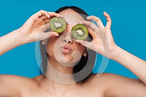 Woman posing isolated over blue wall background with kiwi