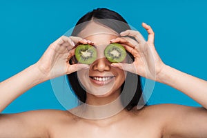 Woman posing isolated over blue wall background with kiwi