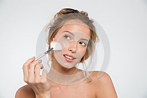 Woman posing isolated over white wall background holding makeup brushes