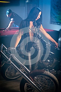 Woman posing near motorbikes, man playing billiards photo