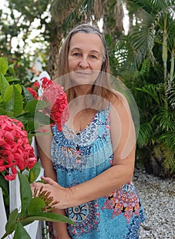 Woman posing next to fence and flowers