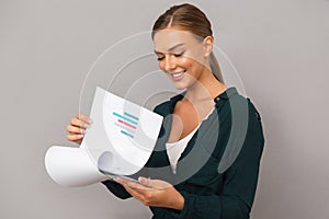 Woman posing over grey wall background holding clipboard with graphics.