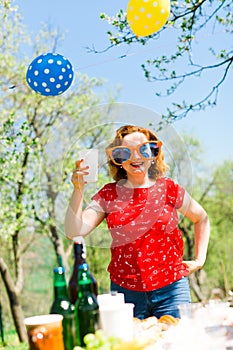 Woman posing in red dress and big funny sun glasses on garden