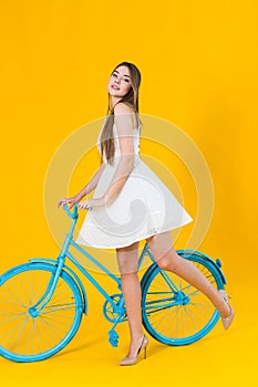 Woman posing seated on a blue bicycle photo