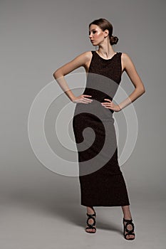Woman posing in a tight long dress. Gray background