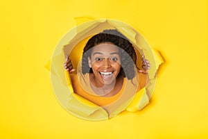 Woman Posing In Torn Paper Looking Through Hole, Yellow Background