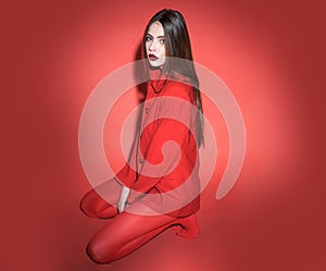 Woman with posing in total red outfit. Fashion concept. Girl on calm face in red formal jacket and tights, red