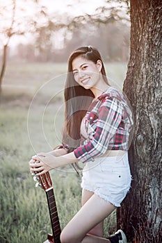 A woman posing with a trusty guitar in the garden photo