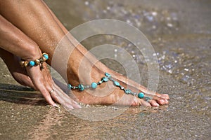 Woman posing on wet sand with bracelets