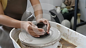 Woman potter hands making a ceramic cup on potter`s wheel, moulding clay