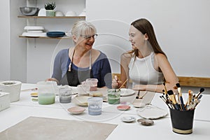 Woman potter with paintbrush glazing ceramic dish on workshop