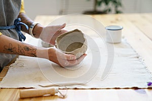 Woman potter sculpting clay pot with hand. Ceramist work with raw earthenware creating craft pottery