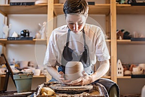 Woman potter working on a Potter`s wheel making a vase. Master pulls the jug off the circle gently holding it in hands