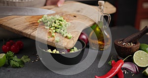 Woman Pouring chopped sliced fresh green avocado fruit into black ceramic bowl at domestic kitchen