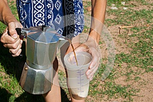 Woman pouring coffee in a bowl with a Moka pot.